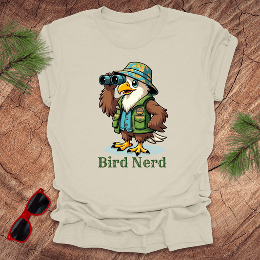 Beige t-shirt with an animated eagle in birdwatching gear with "bird nerd" text on a wood background.