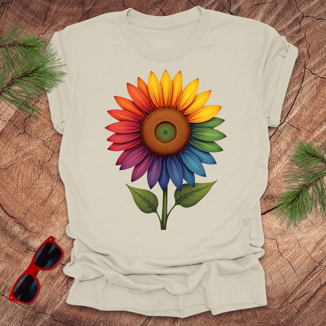 Beige tshirt with a bold rainbow sunflower graphic on a wood background.