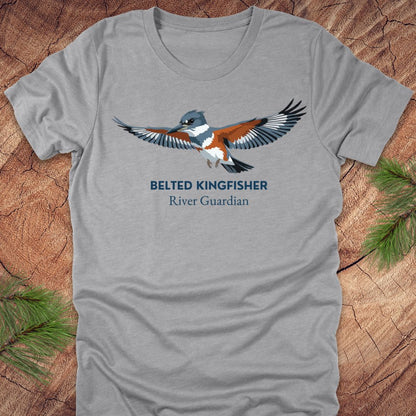 Gray t-shirt with belted kingfisher design and text, 'belted kingfisher river guardian'on a wooden surface