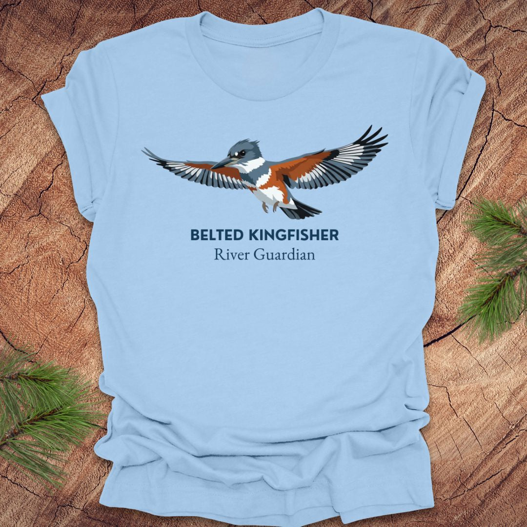Baby blue t-shirt with belted kingfisher design and text, 'belted kingfisher river guardian'on a wooden surface