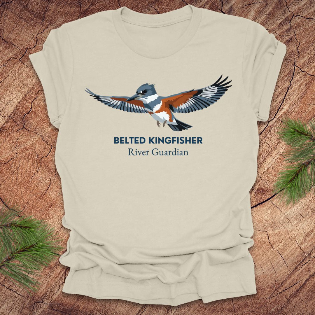 Beige t-shirt with belted kingfisher design and text, 'belted kingfisher river guardian'on a wooden surface
