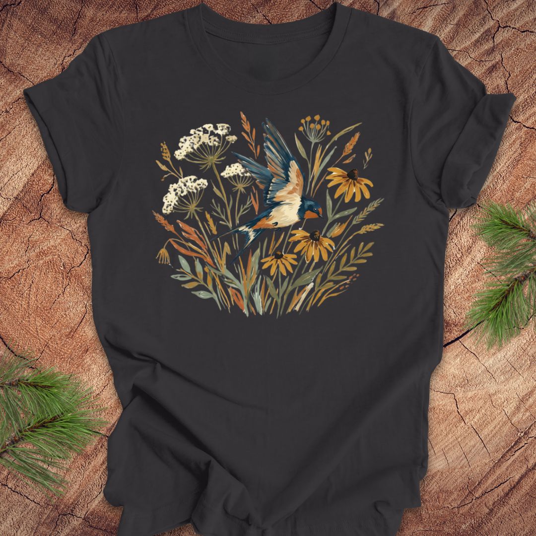 Dark gray t-shirt with watercolor flowers and a barn swallow in flight, on a wood background. 
