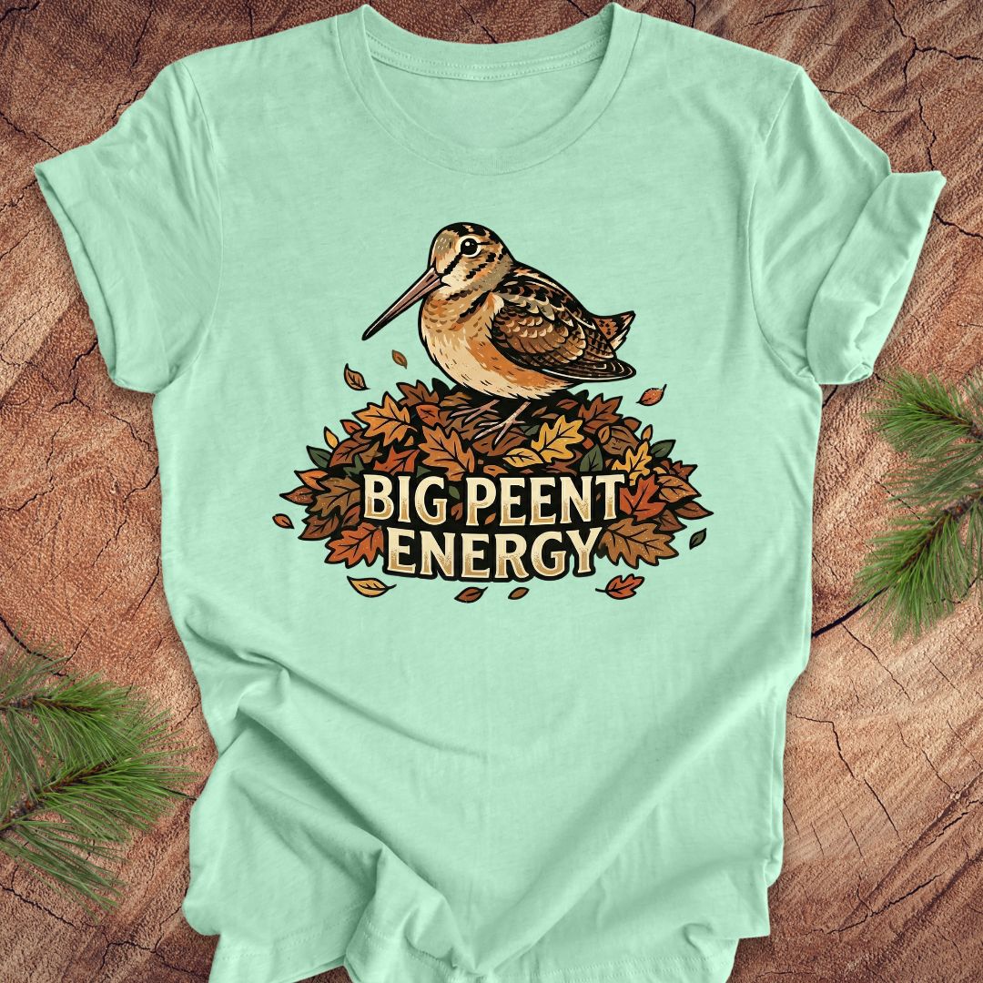 Mint green t-shirt with a woodcock graphic and 'BIG PEENT ENERGY' text on a wooden surface.