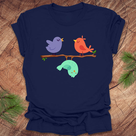 Navy blue t-shirt with cartoon birds on a branch with one upside down, on a wooden surface
