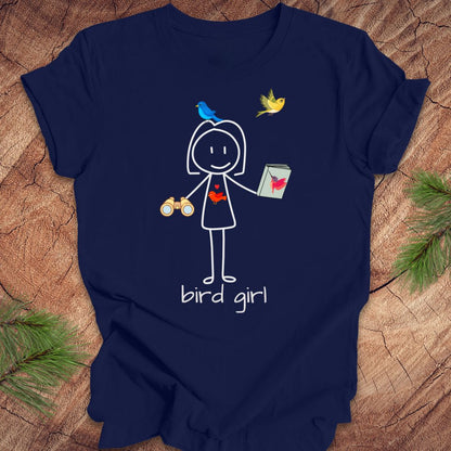 Navy blue t-shirt with a stick figure design labeled 'bird girl' on a wooden surface.