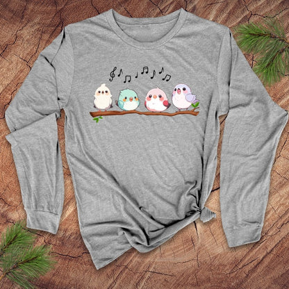 Gray long sleeve t-shirt with four cartoon birds on a branch with musical notes over them, on a wooden background.
