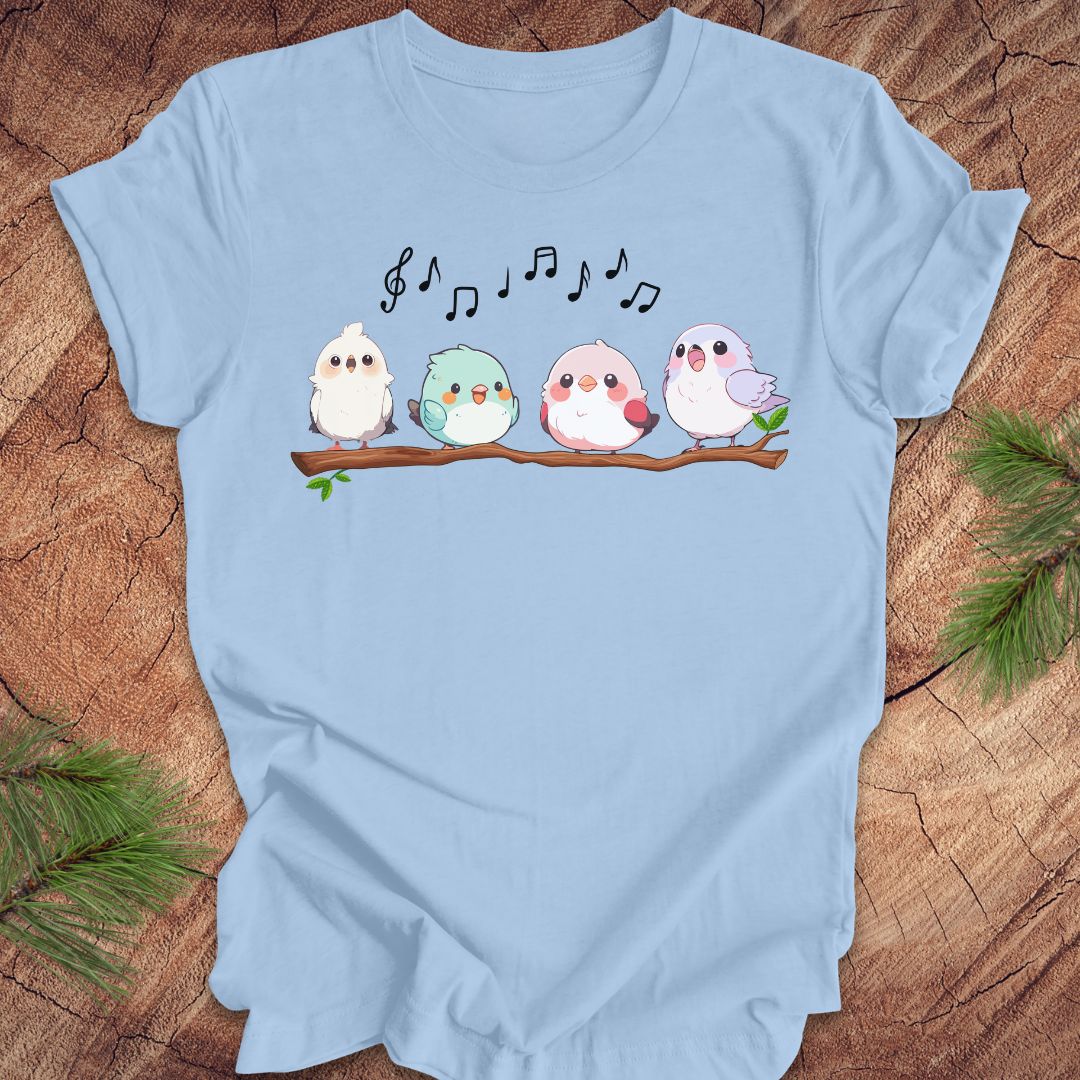 Light blue t-shirt with cartoon birds and musical notes on a wooden surface