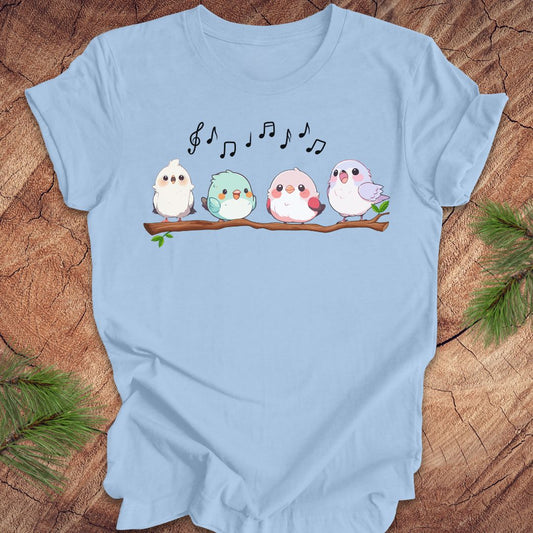 Light blue t-shirt with cartoon birds and musical notes on a wooden surface