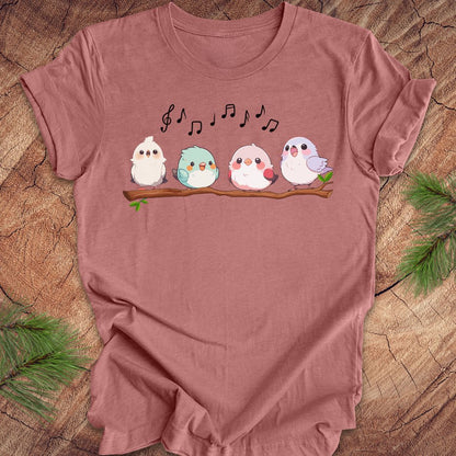 Mauve t-shirt with cartoon birds and musical notes on a wooden surface