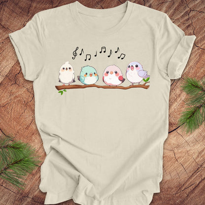 Beige t-shirt with cartoon birds and musical notes on a wooden surface