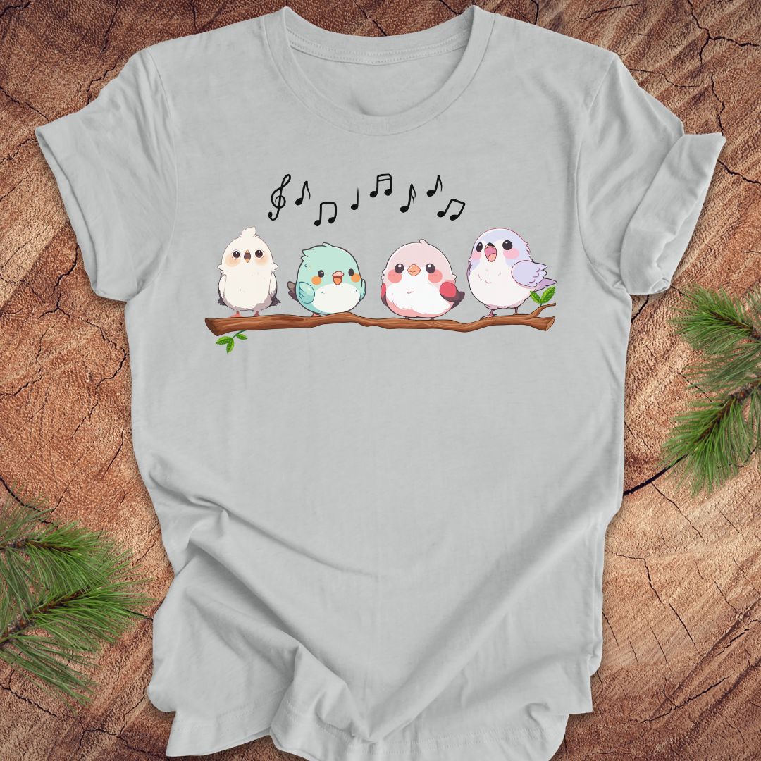 Light gray t-shirt with cartoon birds and musical notes on a wooden surface