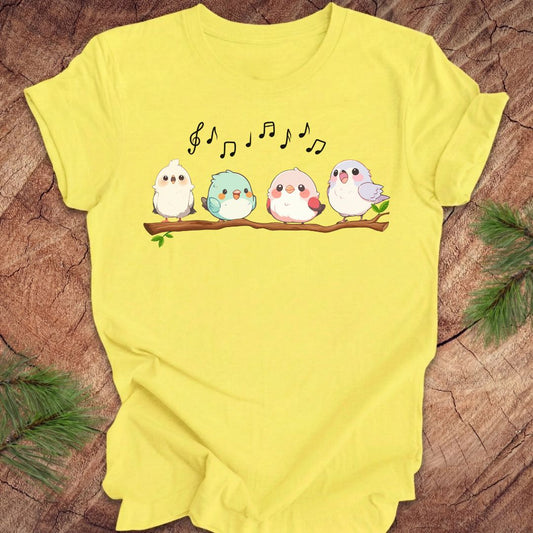 Yellow t-shirt with cartoon birds and musical notes on a wooden surface