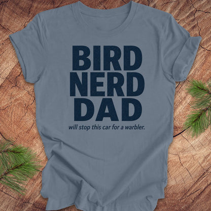 Blue t-shirt with 'BIRD NERD DAD' text on a wooden surface with pine branches.