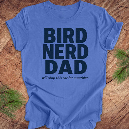 Blue t-shirt with 'BIRD NERD DAD' text on a wooden surface with greenery.