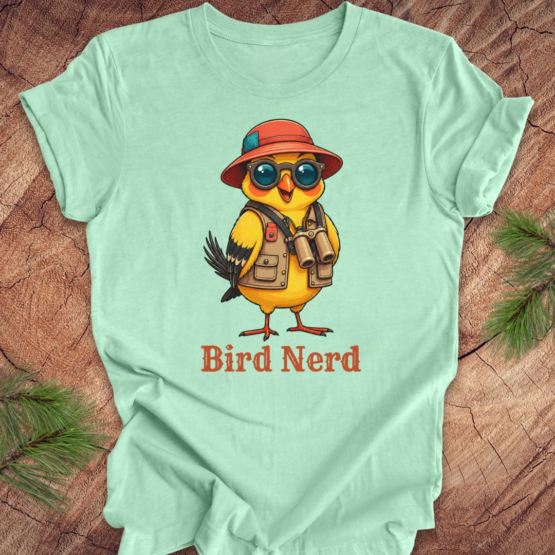 Mint green t-shirt with a cartoon bird wearing a hat and sunglasses on a wooden surface.