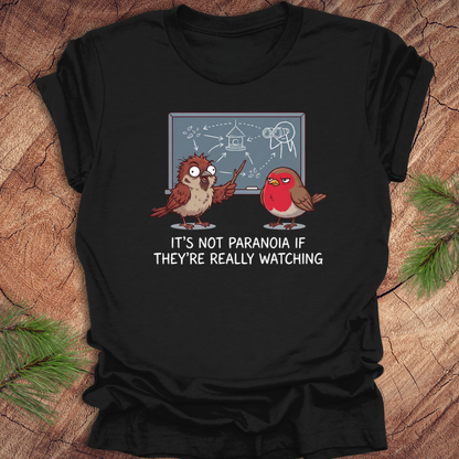 Black t-shirt with cartoon birds and text on a wooden surface