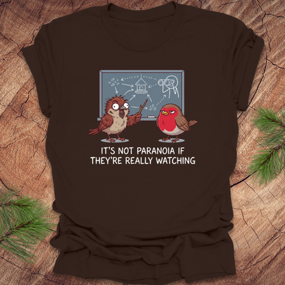Brown t-shirt with cartoon birds and text on a wooden surface