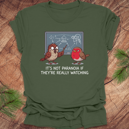 Green t-shirt with cartoon birds and text on a wooden surface