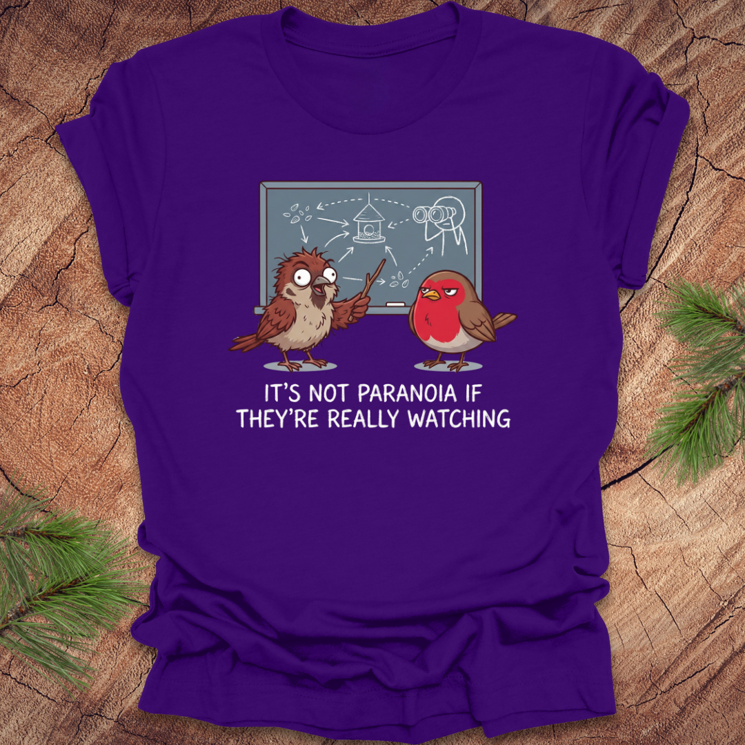 Purple t-shirt with cartoon birds and text on a wooden surface