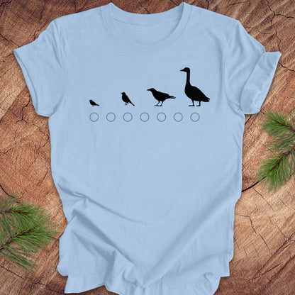 Light blue t-shirt with black bird size graphic on a wooden surface