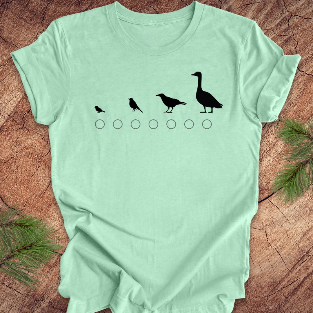Light green t-shirt with black bird graphic on a wooden surface