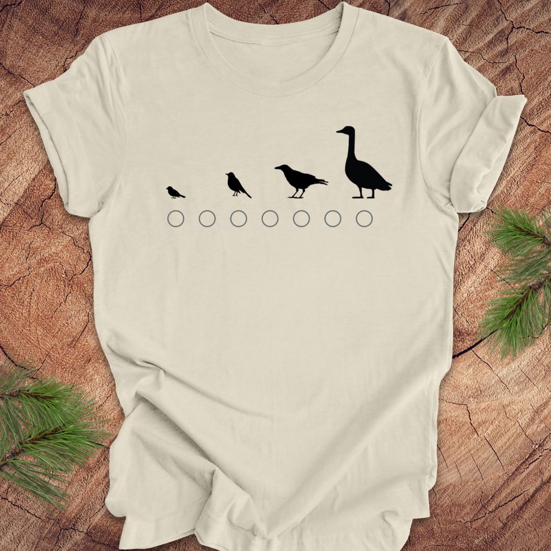 Beige t-shirt with black bird illustrations on a wooden surface