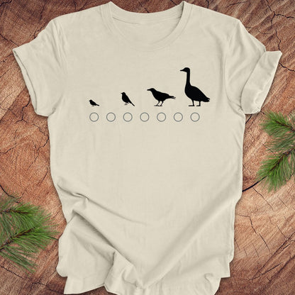 Beige t-shirt with black bird illustrations on a wooden surface