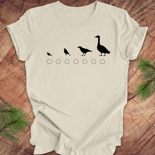 Beige t-shirt with black bird illustrations on a wooden surface