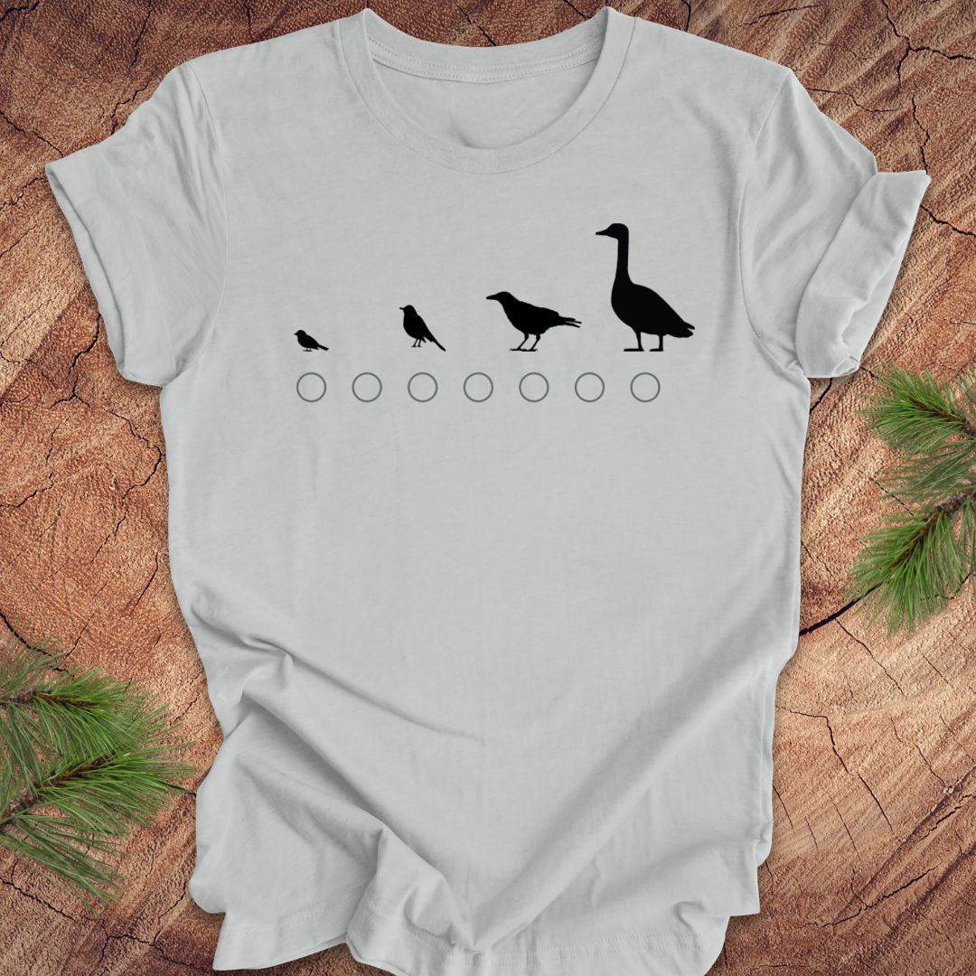 Silver t-shirt with black bird illustrations on a wooden surface
