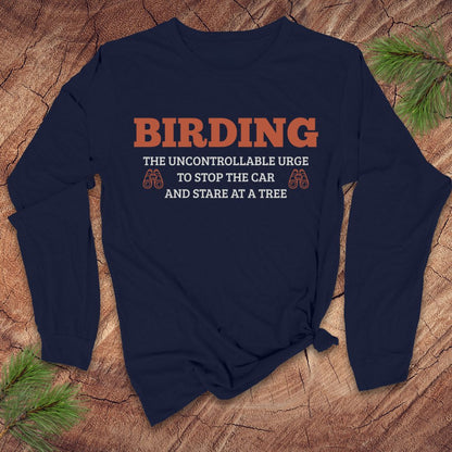 Navy blue long sleeve tshirt with funny 'BIRDING' text on a wooden surface with pine branches.
