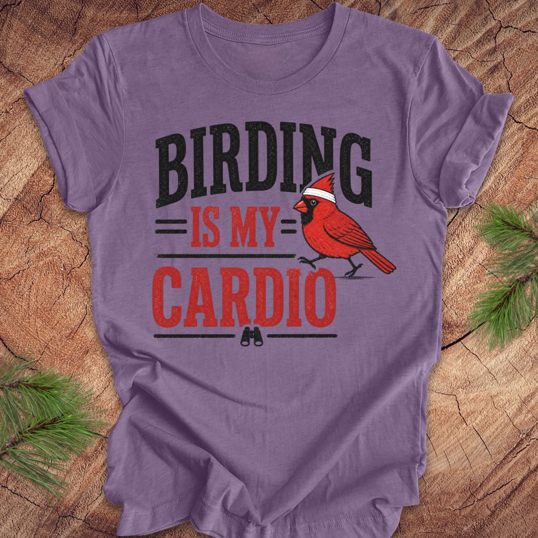 Purple t-shirt with a red cardinal graphic and text 'BIRDING IS MY CARDIO' on a wooden surface.