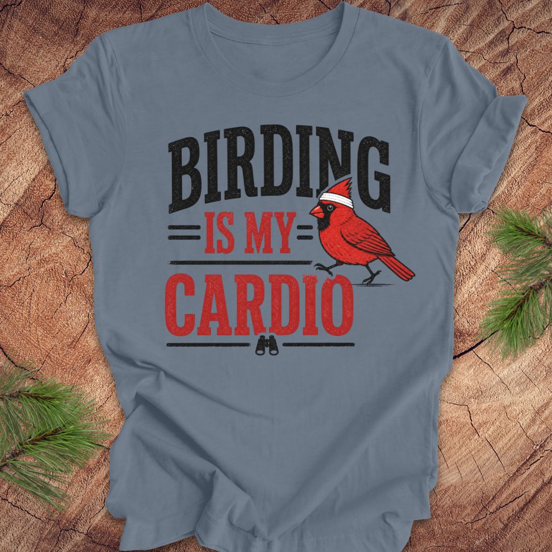 Blue t-shirt with 'BIRDING IS MY CARDIO' text and a red cardinal graphic on a wooden surface.