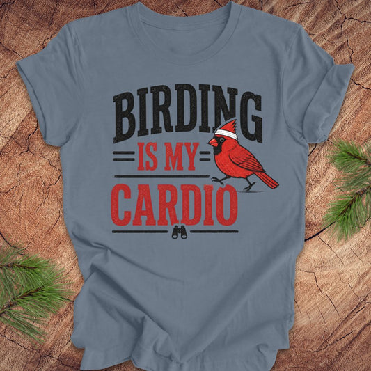 Blue t-shirt with 'BIRDING IS MY CARDIO' text and a red cardinal graphic on a wooden surface.