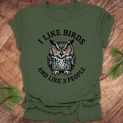 Green t-shirt with an owl graphic and text, 'i like birds and like 3 people' on a wooden surface