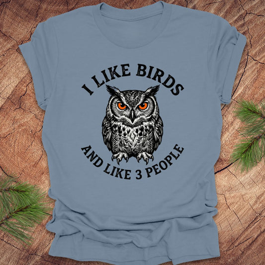 Blue t-shirt with an owl graphic and text, 'i like birds and like 3 people' on a wooden surface