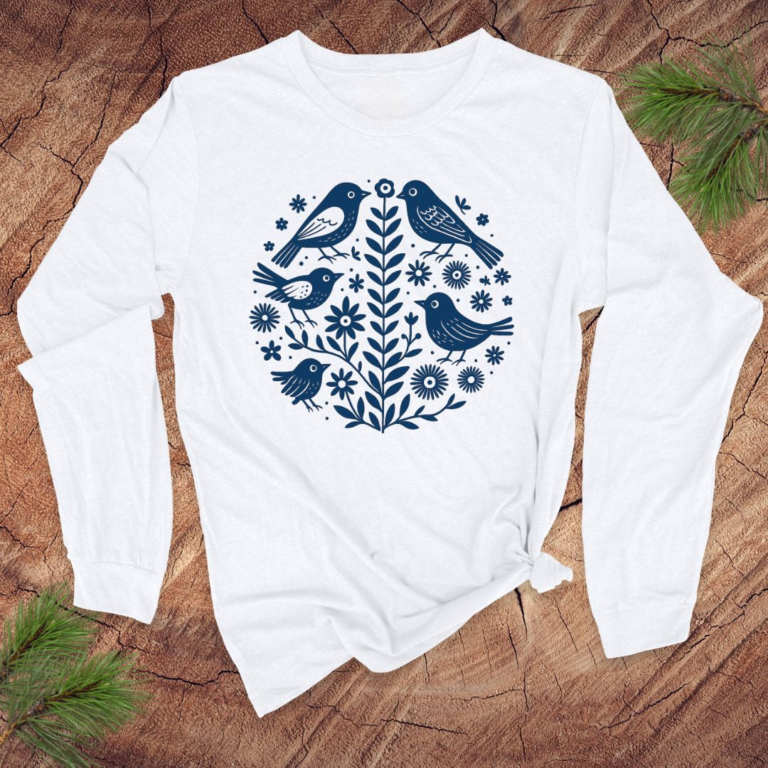 White long-sleeve t-shirt with blue bird and floral pattern on a wooden surface