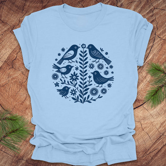 Baby blue t-shirt with folk art blue bird and floral design on a wooden surface