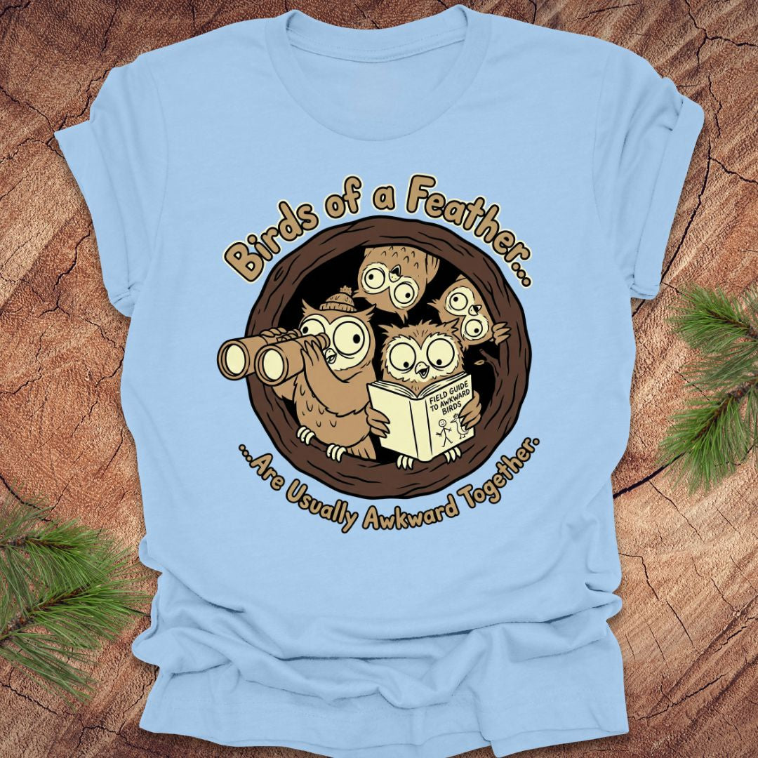 Light blue t-shirt with owl design and text on a wooden surface