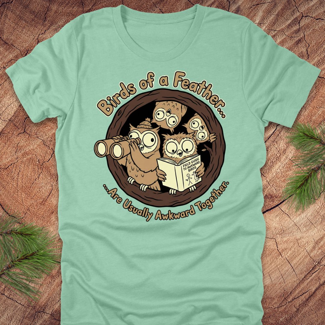 Light green t-shirt with cartoon owls design on a wooden surface
