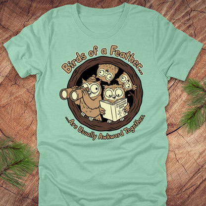 Light green t-shirt with cartoon owls design on a wooden surface