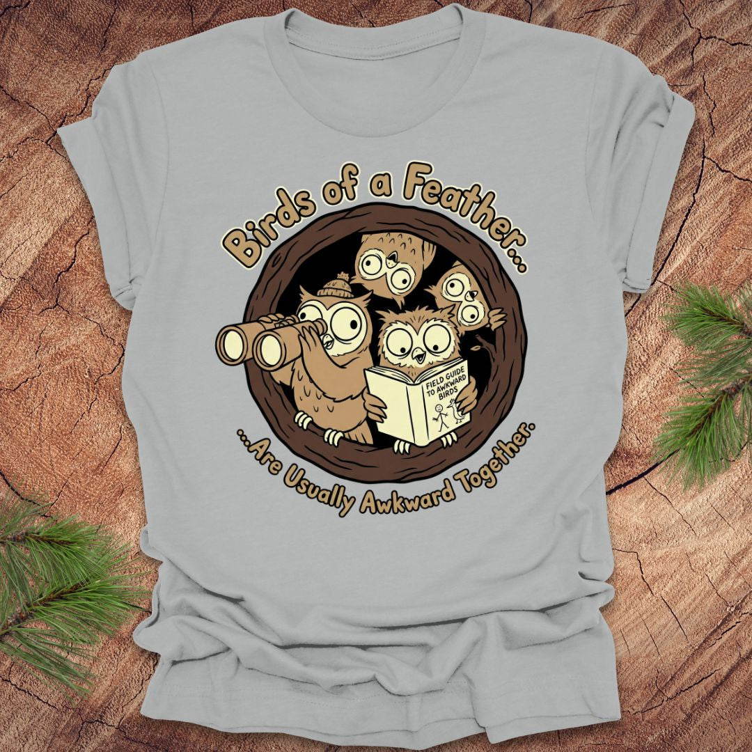 Gray t-shirt with cartoon owls design on a wooden surface