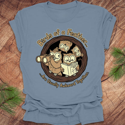 Blue t-shirt with owl design and text on a wooden background