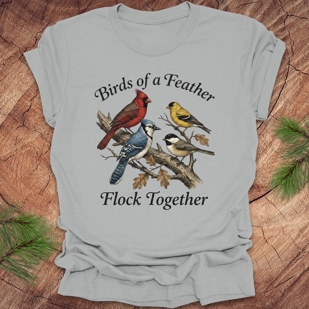 Gray t-shirt with bird illustration and text on a wooden surface