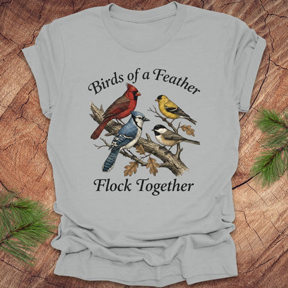 Gray t-shirt with bird illustration and text on a wooden surface