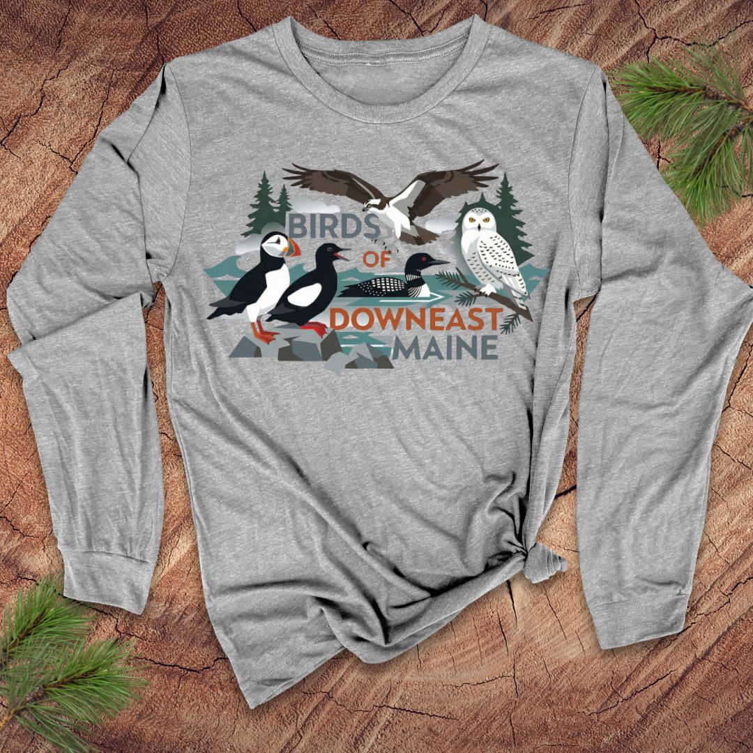 Gray long-sleeve shirt with bird graphic and 'Birds of Downeast Maine' text on a wooden surface.