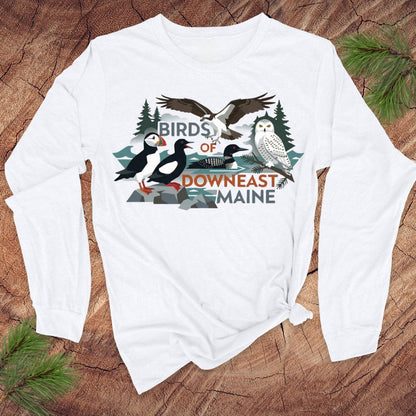 White long-sleeve shirt with 'Birds of Downeast Maine' design on a wooden surface.