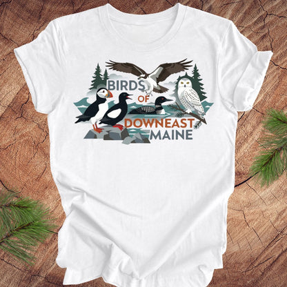 White t-shirt with birds of downeast maine graphics and text on a wooden surface