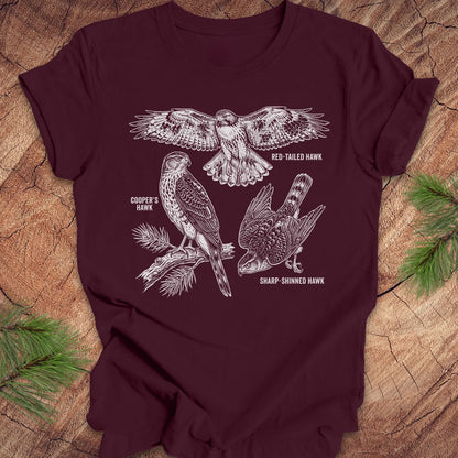 Maroon t-shirt with hawk illustrations on a wooden surface