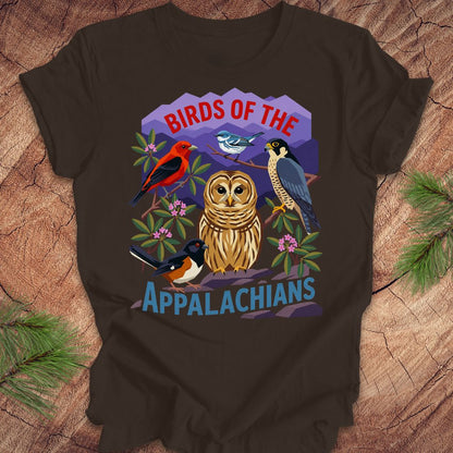 Brown t-shirt with 5 birds and text, 'birds of the appalachians' on a wood background.