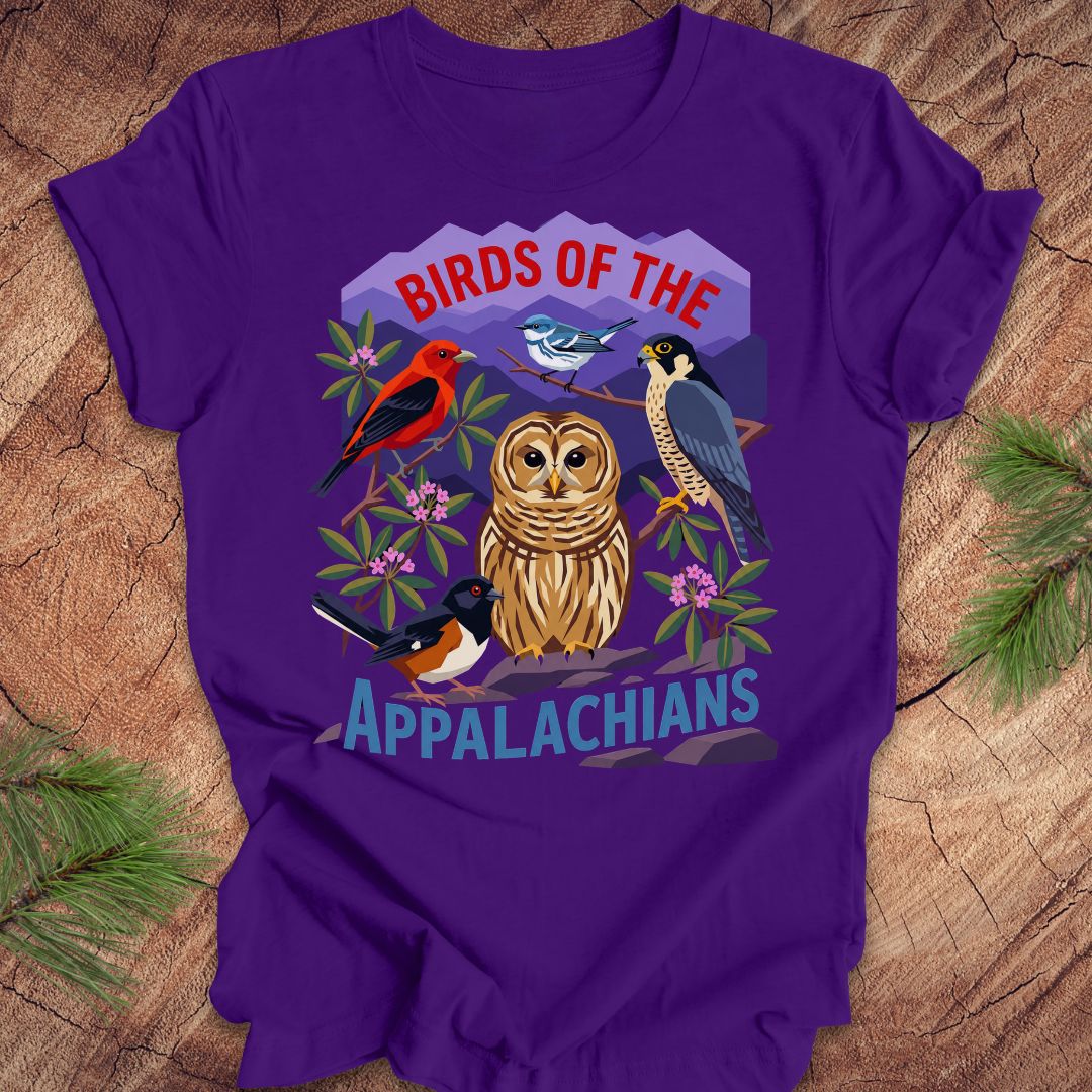 Purple t-shirt with 5 birds and text, 'birds of the appalachians' on a wood background.